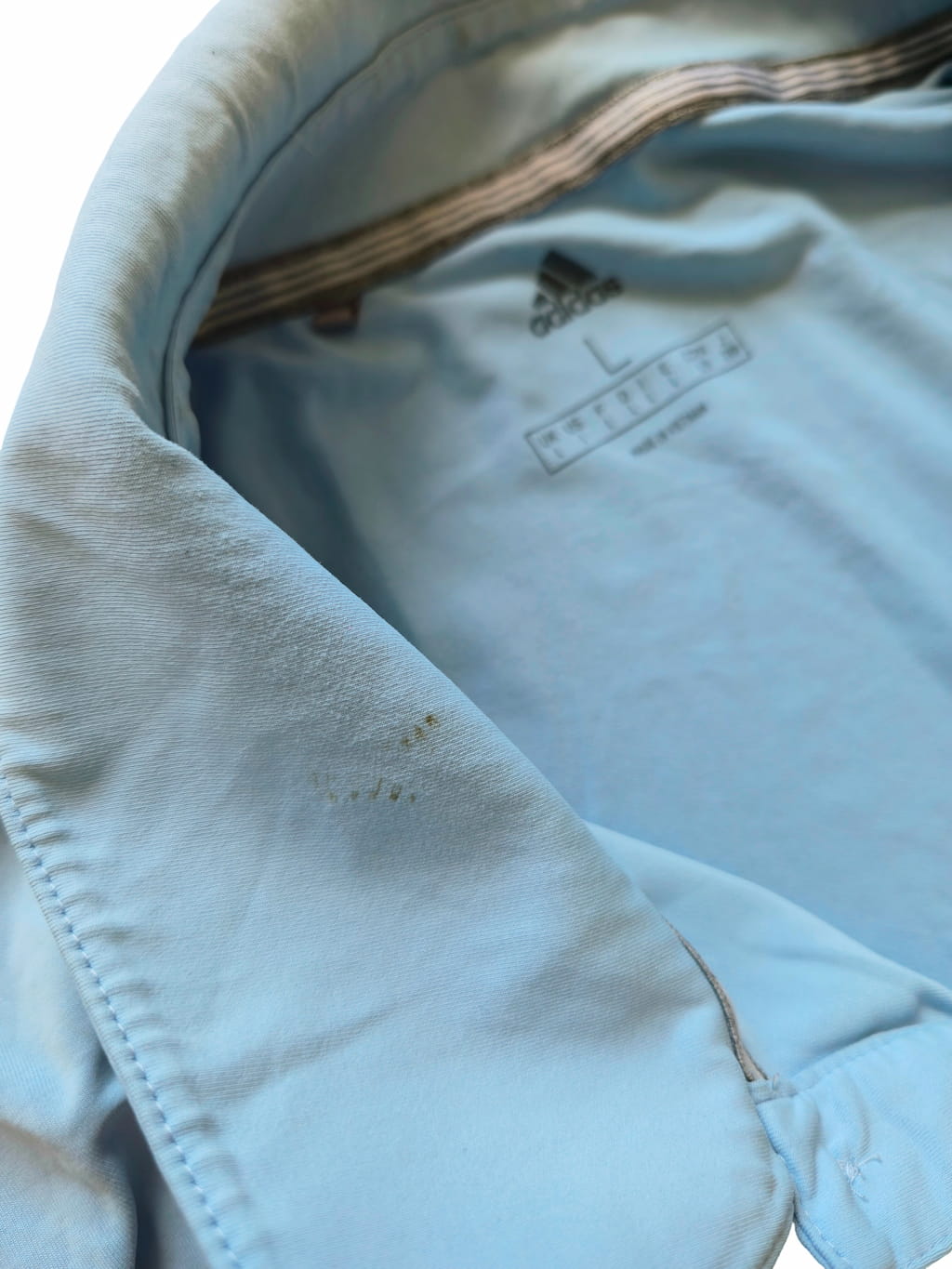 Détail zoomé d'un défaut sur un t-shirt adidas bleue issu d'un lot Grade B.