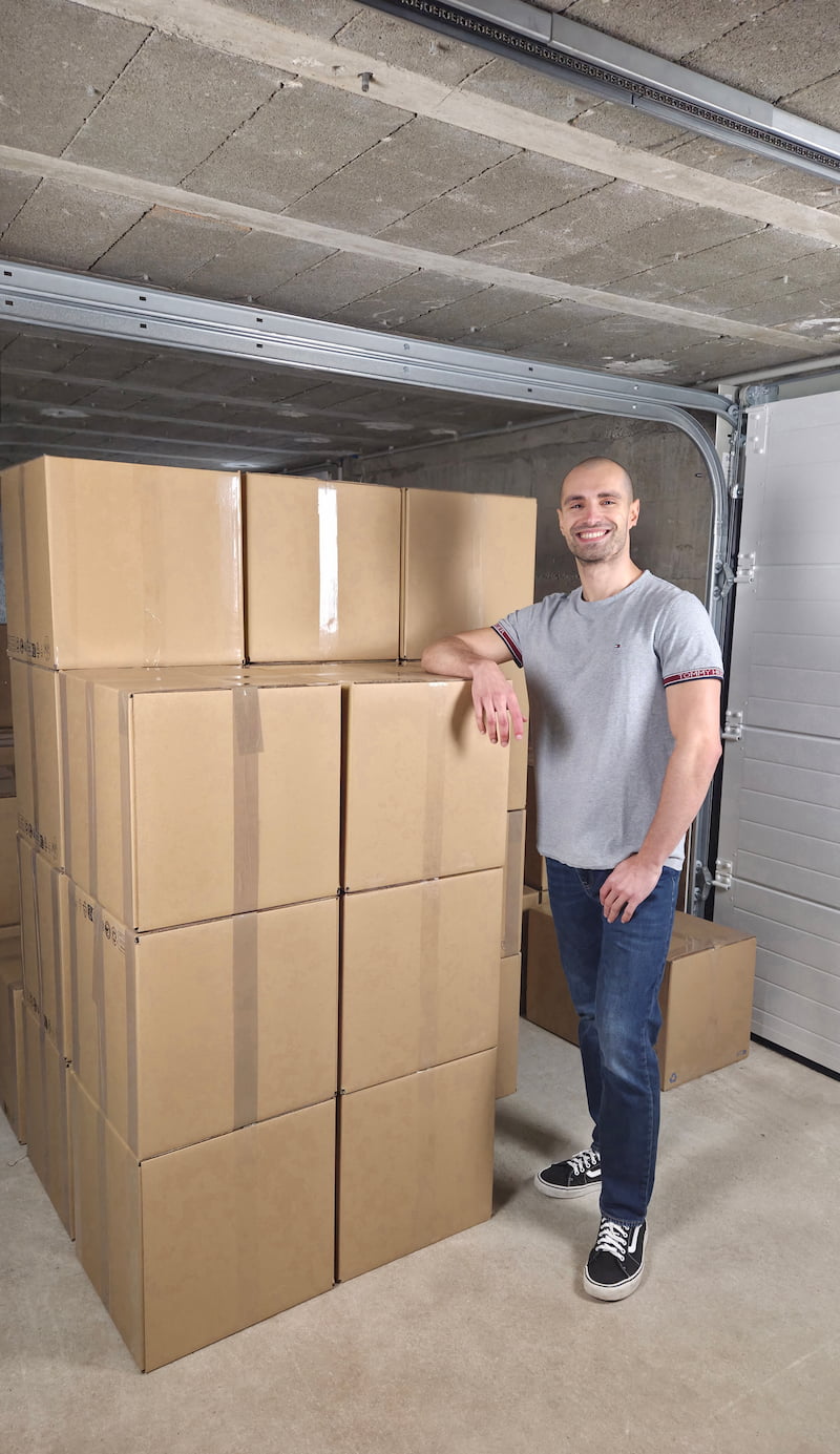 Le fondateur de IRONBALE dans son entrepôt devant des cartons de vêtements préparés pour l'expédition aux revendeurs.